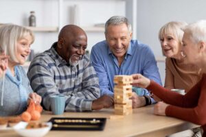 An older adult and a family member packing boxes in a cozy living room filled with personal belongings.