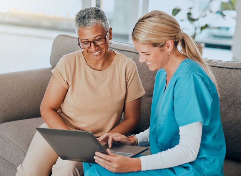 Older adult speaking with a caregiver in a bright, accessible assisted living apartment.